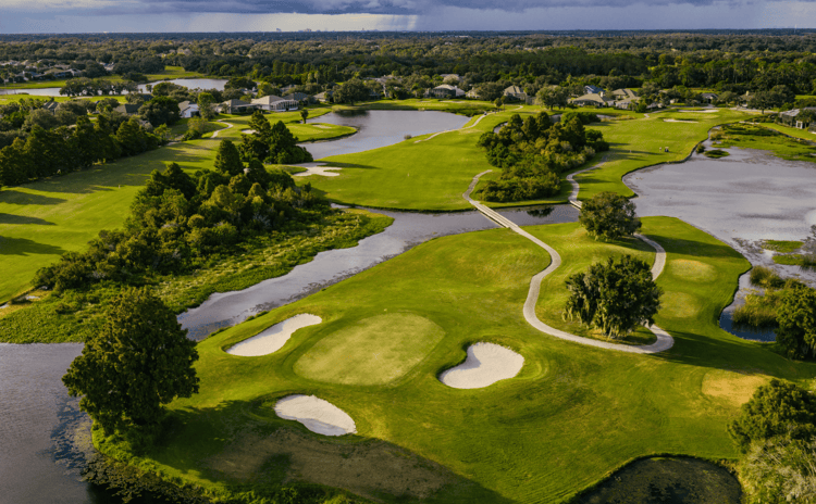 Aerial view of green Kissimmee Bay golf course featuring fairways, greens, sand bunkers, and ponds.